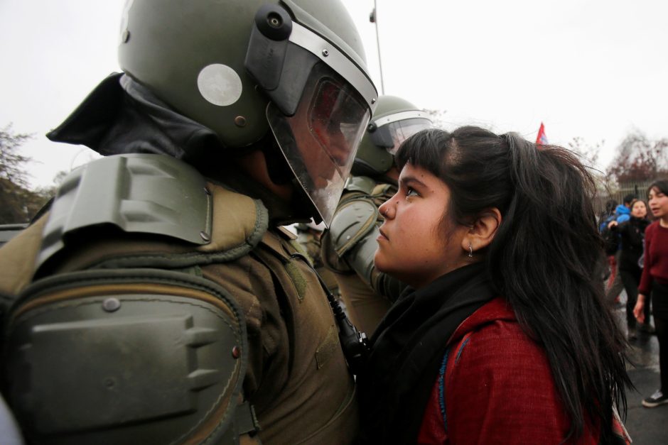 Una manifestante chilena mira a un policia antidisturbios durante una protesta en el aniversario del golpe de estado de 1973 (Santiago, Chile 11 de septiembre de 2016) © Carlos Vera Mancilla/Reuters