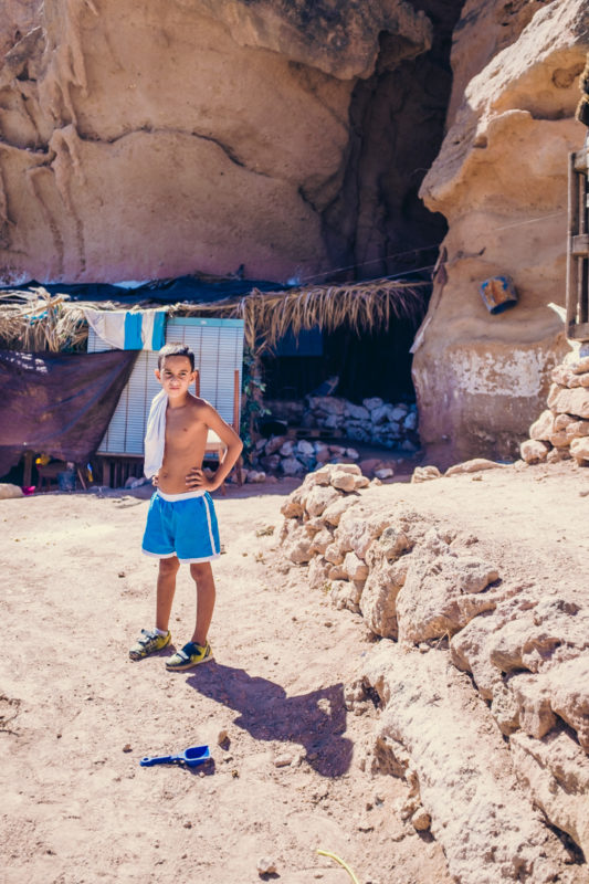 Un niño posa delante de una cueva en el cerro de las Mellizas